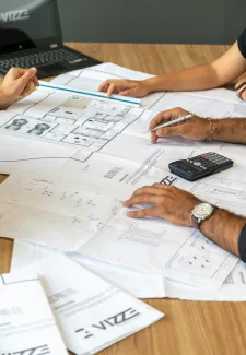 people reviewing architectural blueprints on desk by Pedro Miranda courtesy of Unsplash.