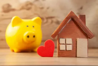 Yellow piggy bank with wooden house and red heart by Sasun Bughdaryan courtesy of Unsplash.