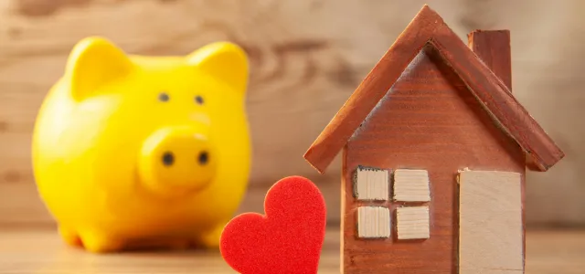 Yellow piggy bank with wooden house and red heart by Sasun Bughdaryan courtesy of Unsplash.