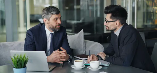 two men sitting at a table having a conversation by Vitaly Gariev courtesy of Unsplash.